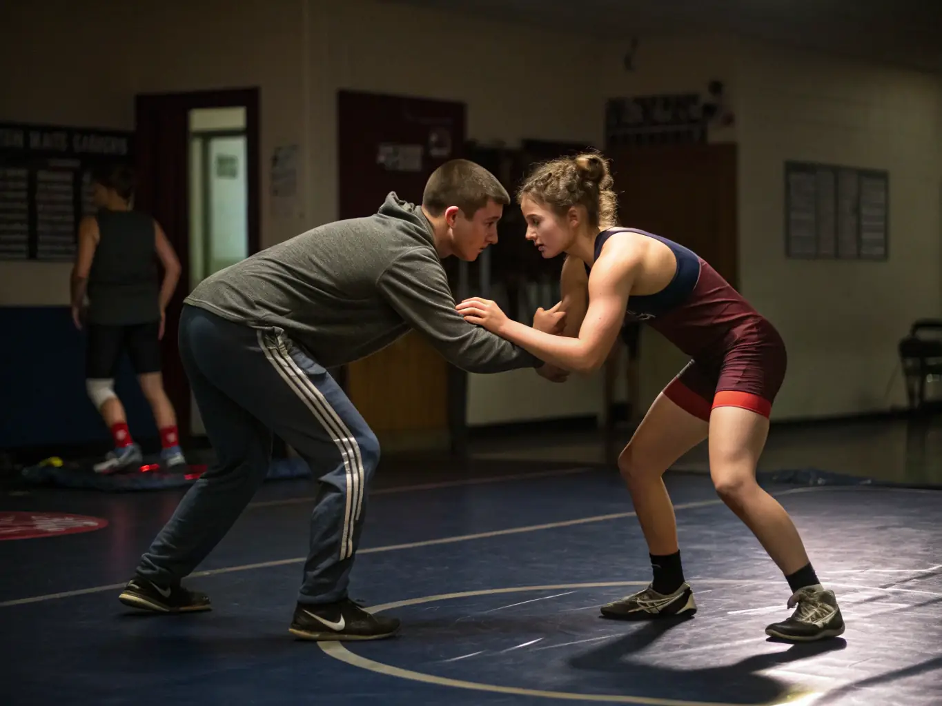 A focused image of a coach providing personalized training to a wrestler, emphasizing technique and strategy, in a well-equipped training center.